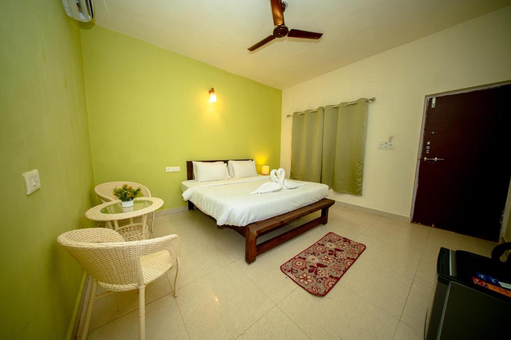a bedroom with a bed and chairs in a room at Aqua Wave by YogiTree Hotels in North goa