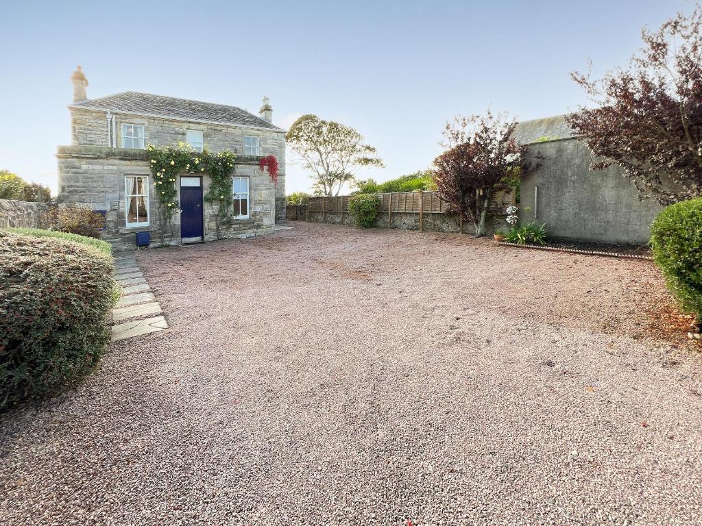 an old stone house with a blue door on a gravel driveway at Ruddon Grange in Elie