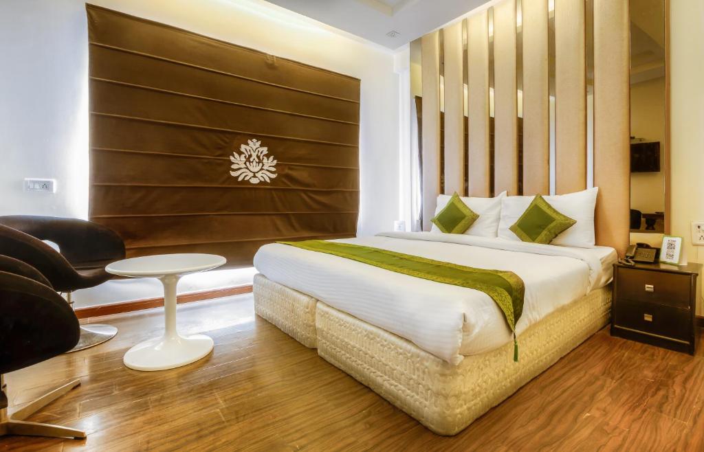 a bedroom with a bed and a chair and a table at Hotel Gold Souk - Karol Bagh in New Delhi
