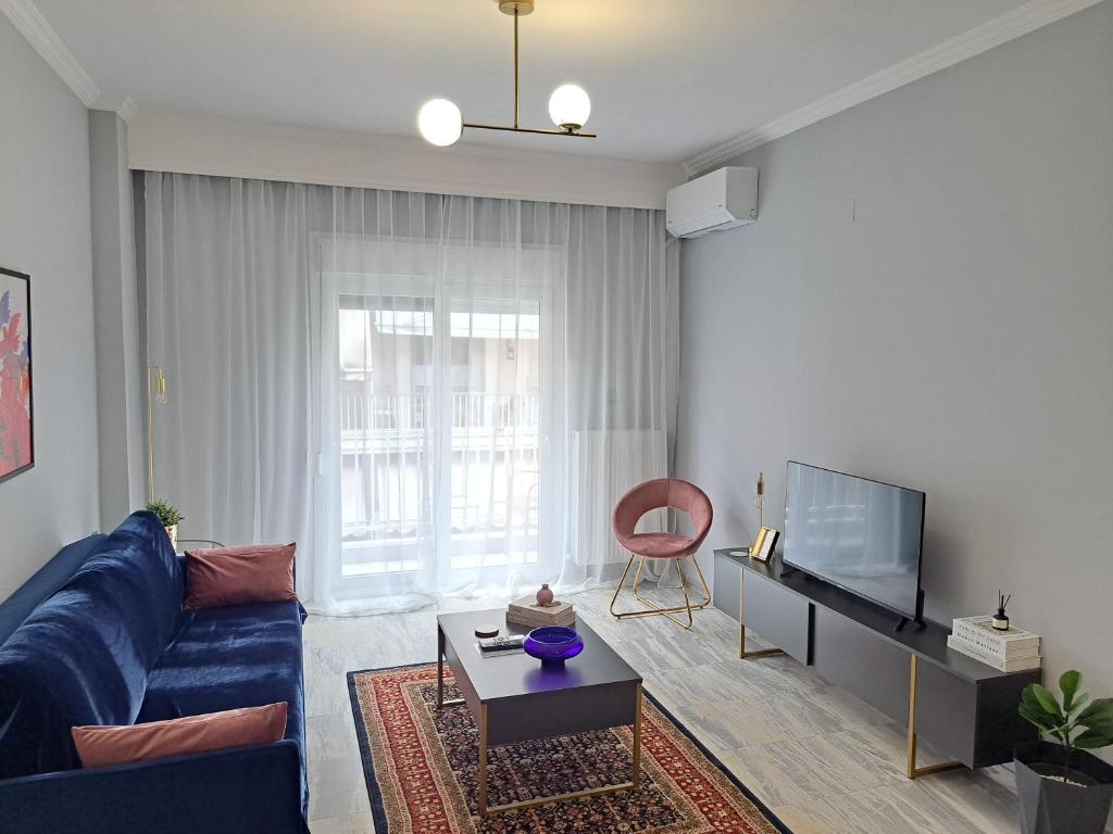 a living room with a blue couch and a tv at Twins Apartments 2 in Serres