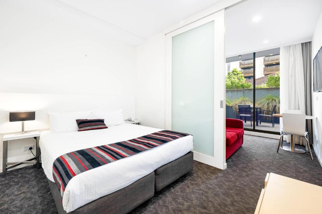 a hotel room with a bed and a red chair at Comfort Apartments Box Hill in Box Hill