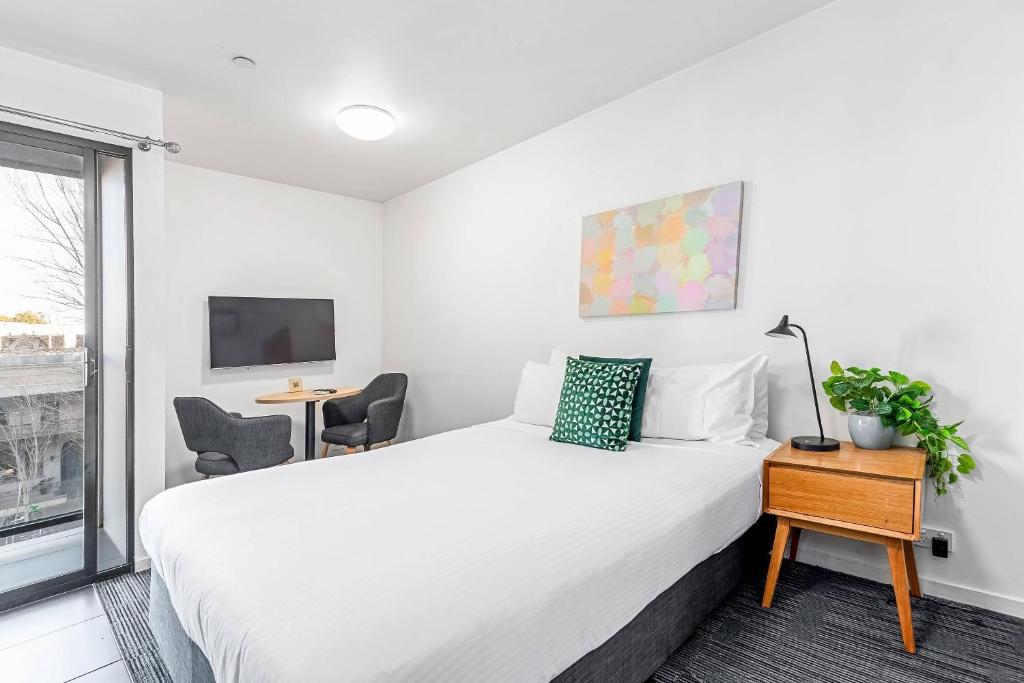 a bedroom with a large white bed and a window at Quality Apartments North Melbourne in Melbourne
