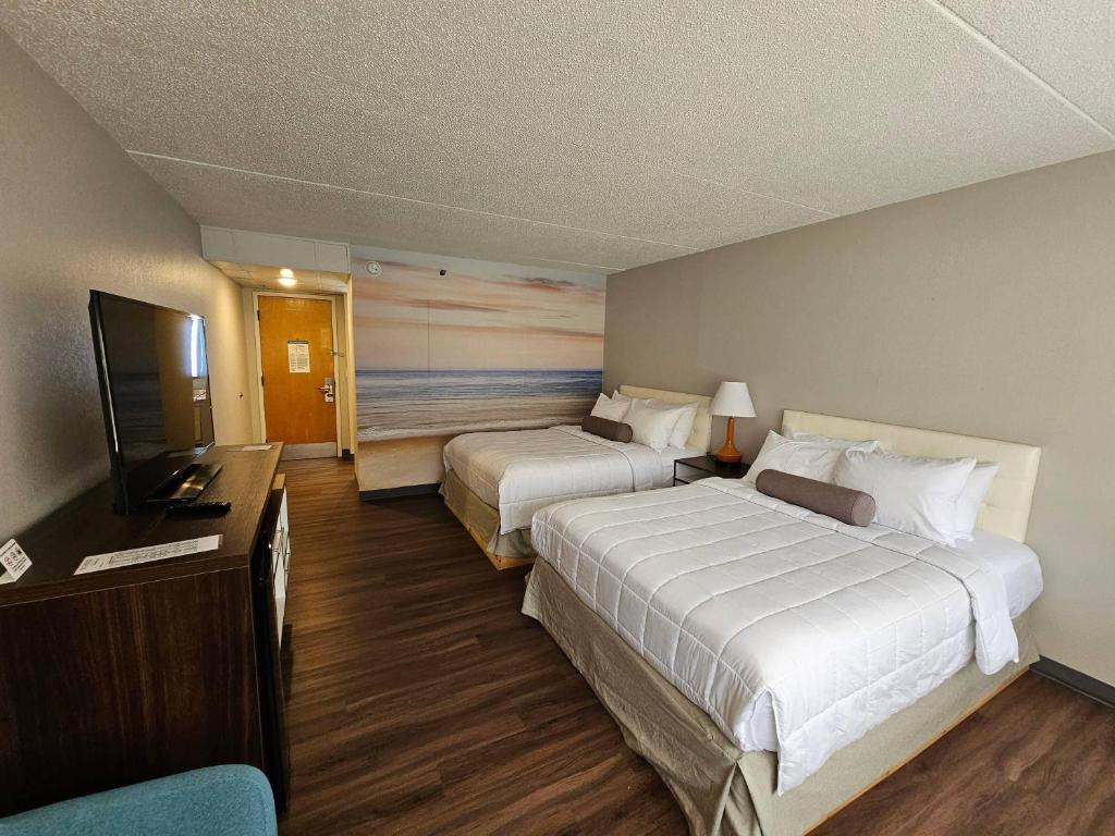 a hotel room with two beds and a flat screen tv at Clarion Pointe South Portland in South Portland