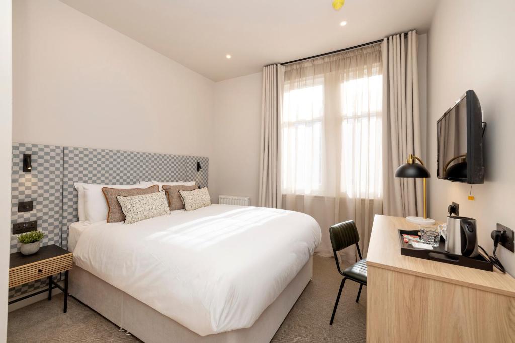 a bedroom with a bed and a desk and a television at Joivy Royal Mile Aparthotel in Edinburgh
