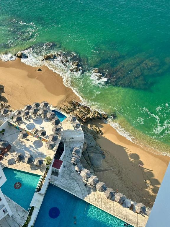 an aerial view of a beach with umbrellas and the ocean at Suite Acapulco vista al mar in Acapulco