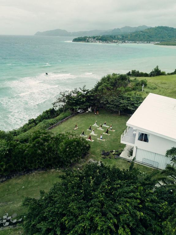 a group of people laying on the grass near the ocean at Balay Kalachuchi in Barili