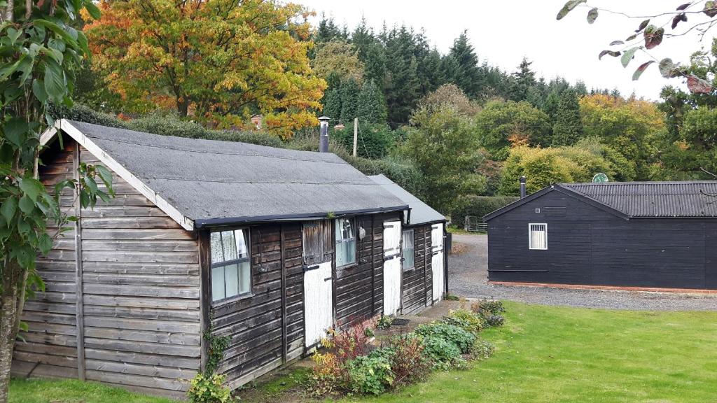 a small cabin with a black roof in a yard at Crockers Farm in Dorking