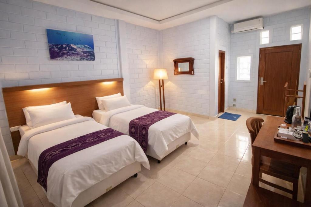 a hotel room with two beds and a desk at Dermaga Resort Pramuka in Pulau Pramuka