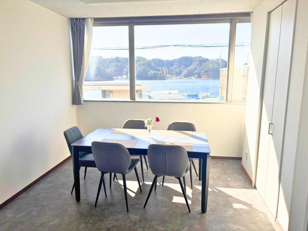 a dining room table with chairs and a large window at Magokoro House 202 in Nishiizu