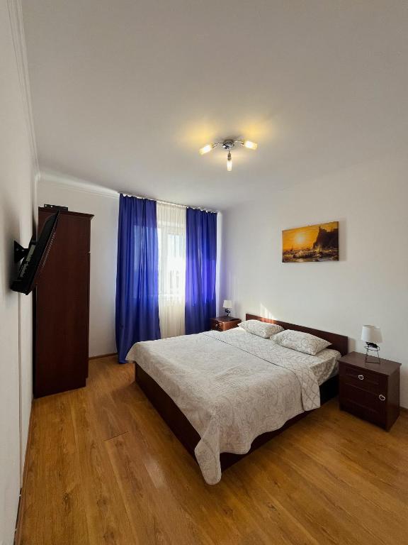 a bedroom with a large bed and blue curtains at Apartments Domovik on Beregovskaya 3 in Mukacheve
