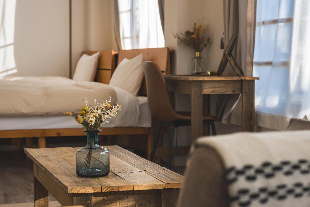 a bedroom with a bed and a vase with flowers on a table at wanderlust STAY in Kofu