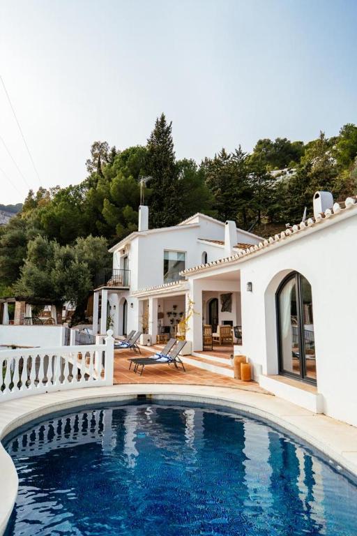 a villa with a swimming pool in front of a house at Hearts & Home in Mijas