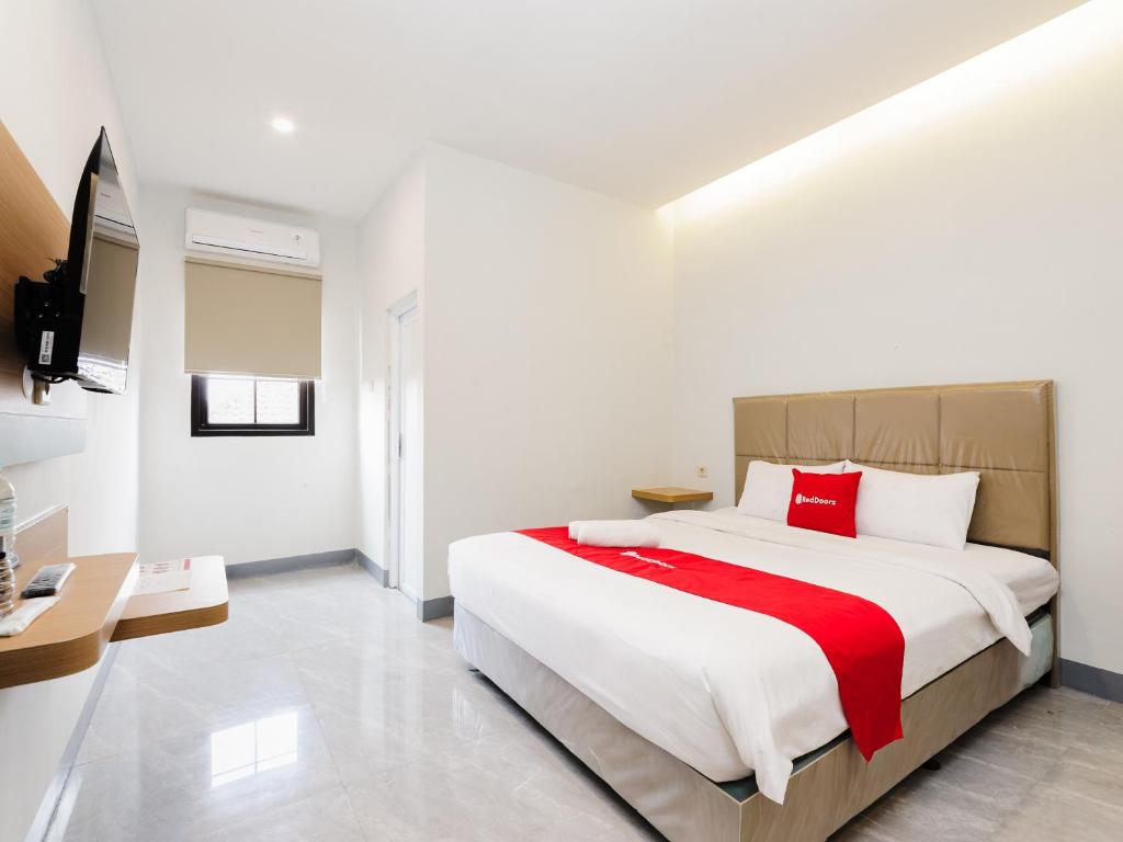 a bedroom with a large white bed with red pillows at RedDoorz Plus Ciapus Bogor in Cimanglid