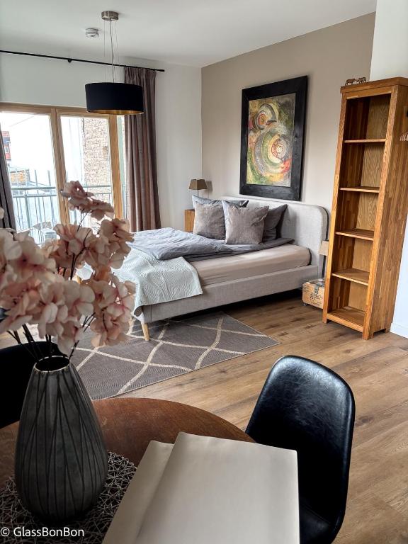 a living room with a bed and a table with a vase at Altstadtflair - Ruppin Quartier Stadtmitte in Neuruppin