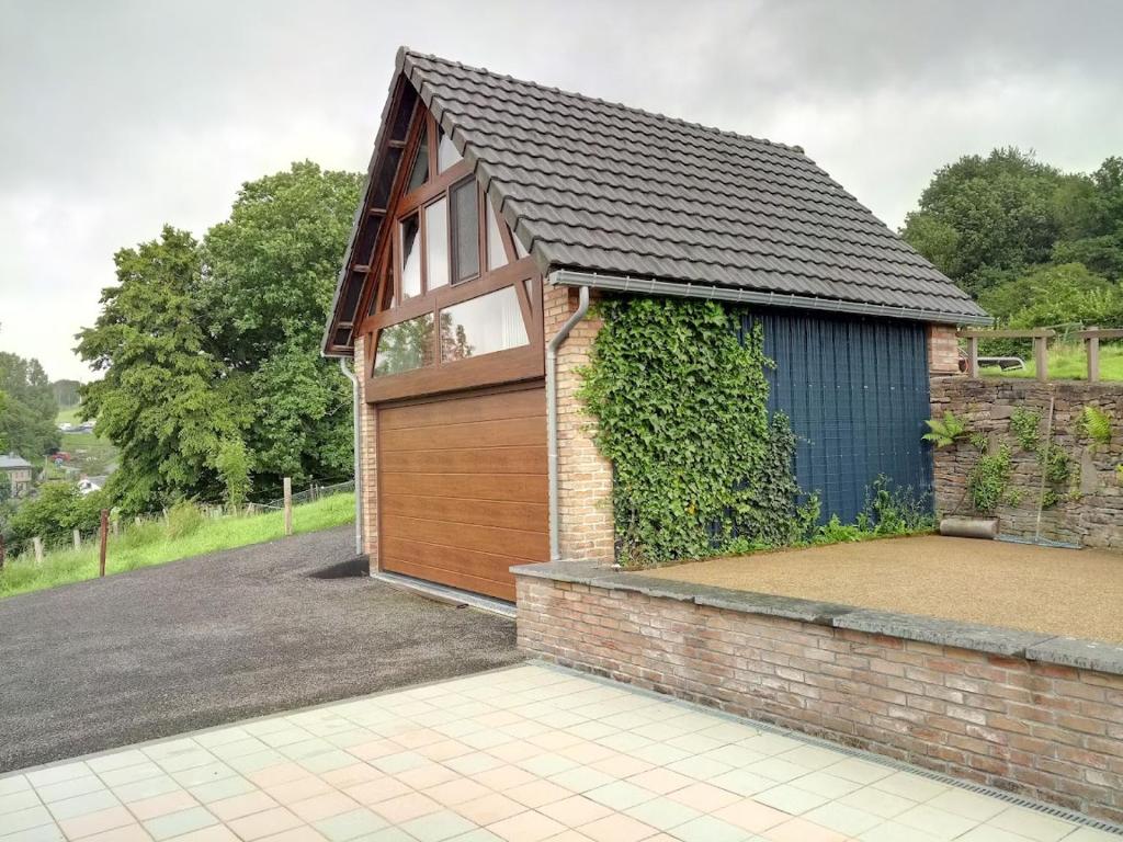 a house with a garage with a ivy at " Al'Coppette " Gîte open-space in Comblain-au-Pont