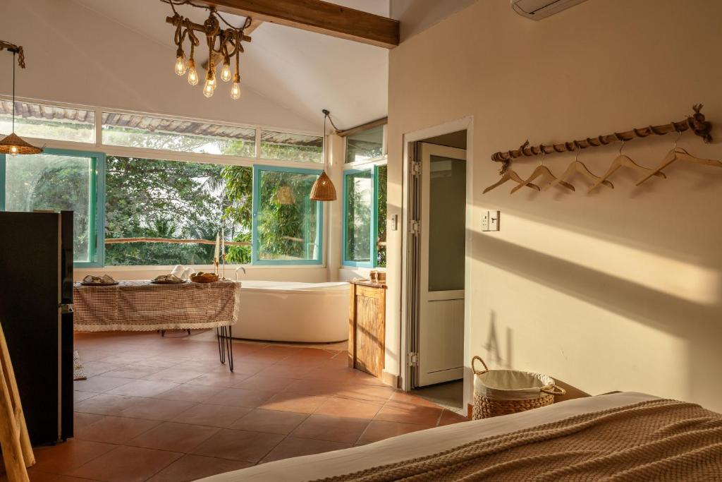 a bedroom with a tub and a sink and a bath room at Êlim House in Phú Quốc