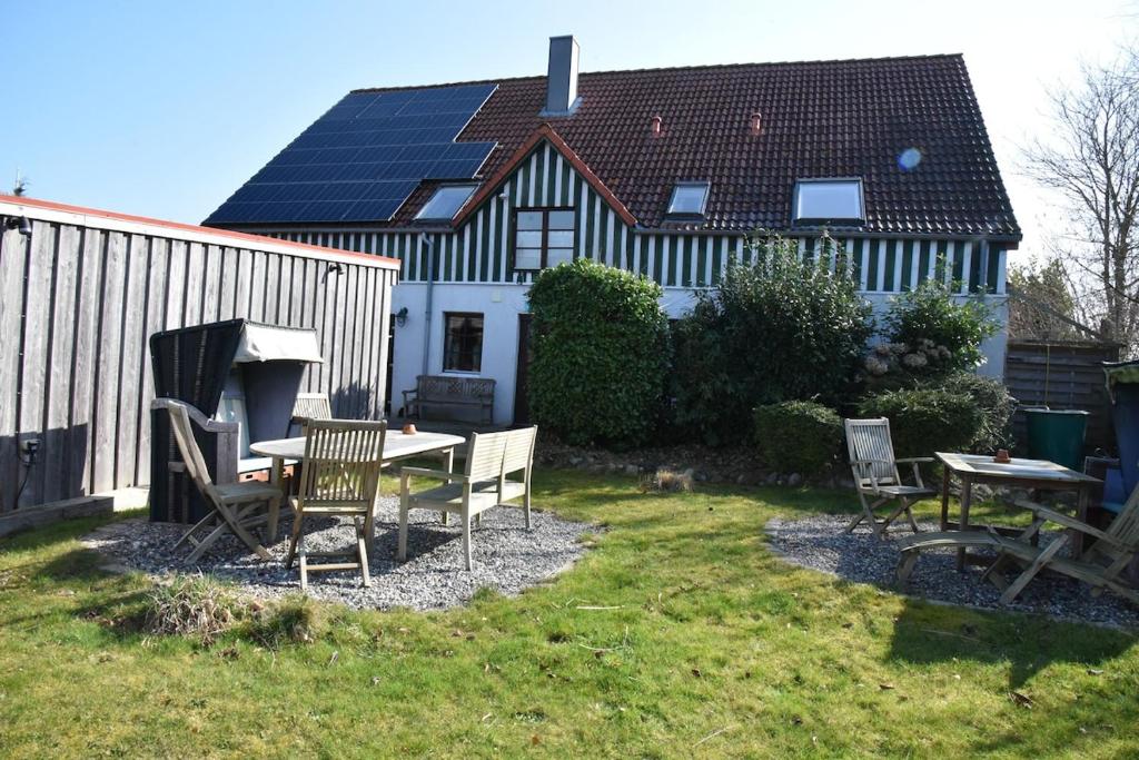 a backyard with a table and chairs and a house with solar panels at Ferienwohnung Ankerpladsen Opti in Behrensdorf