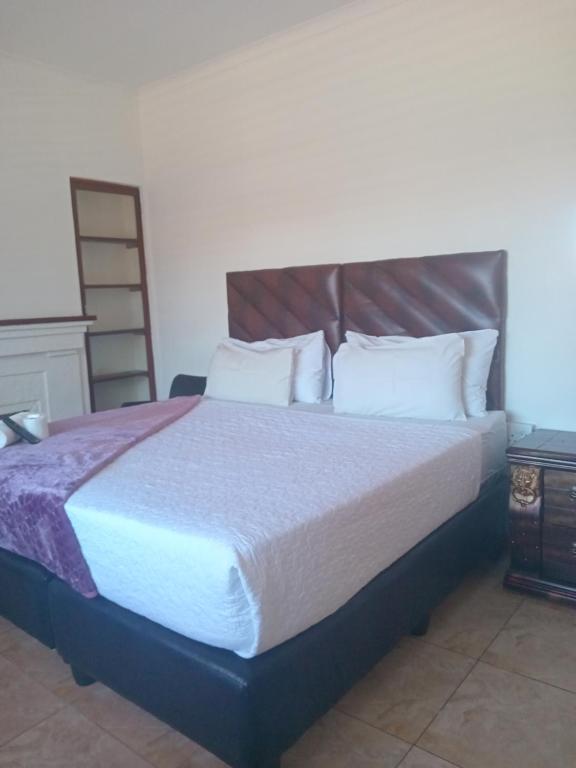 a bedroom with a large bed with white pillows at Duminy Guesthouse in Bellville