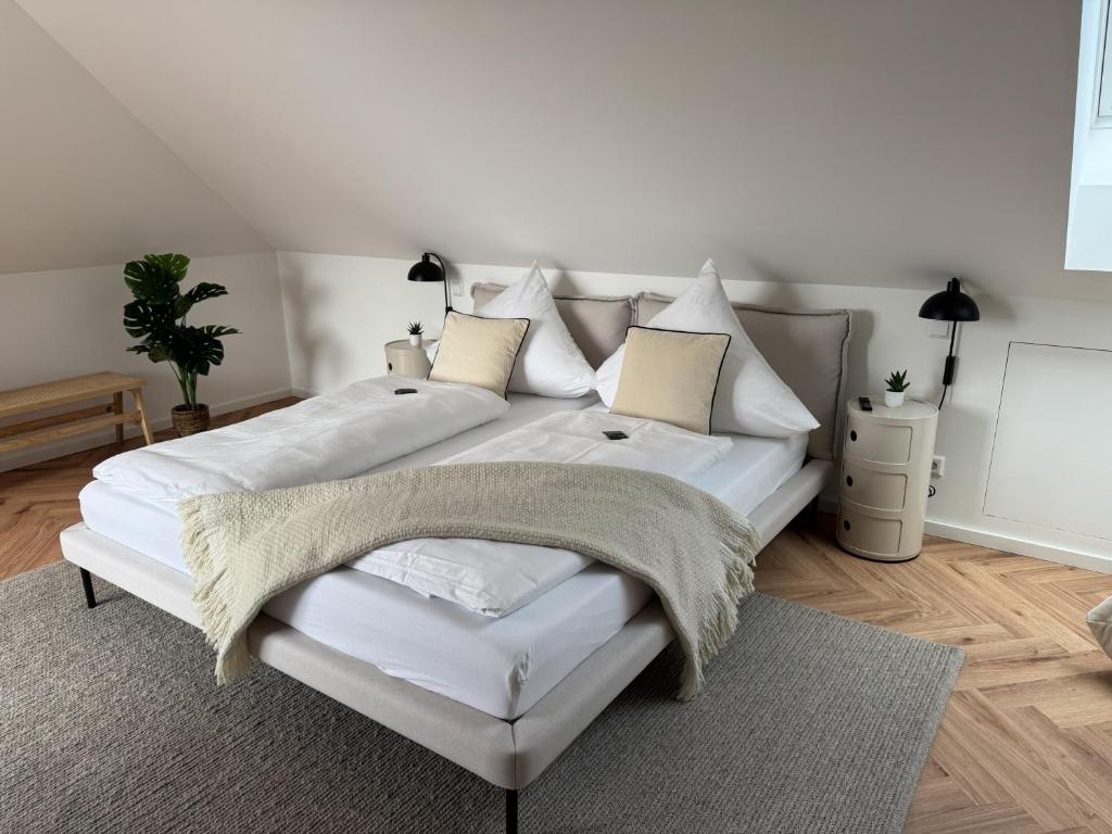 a white bed with white pillows and a blanket at Alte Feuerwache "nur wenige Minuten von Freiburg" in Hugstetten
