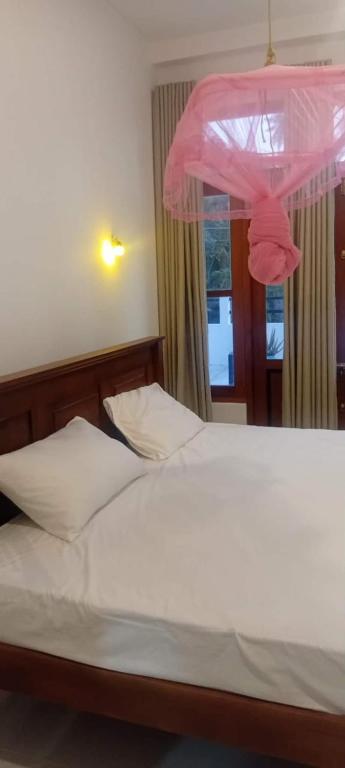 a bedroom with a bed with a pink canopy at Serenity villa in Weligama