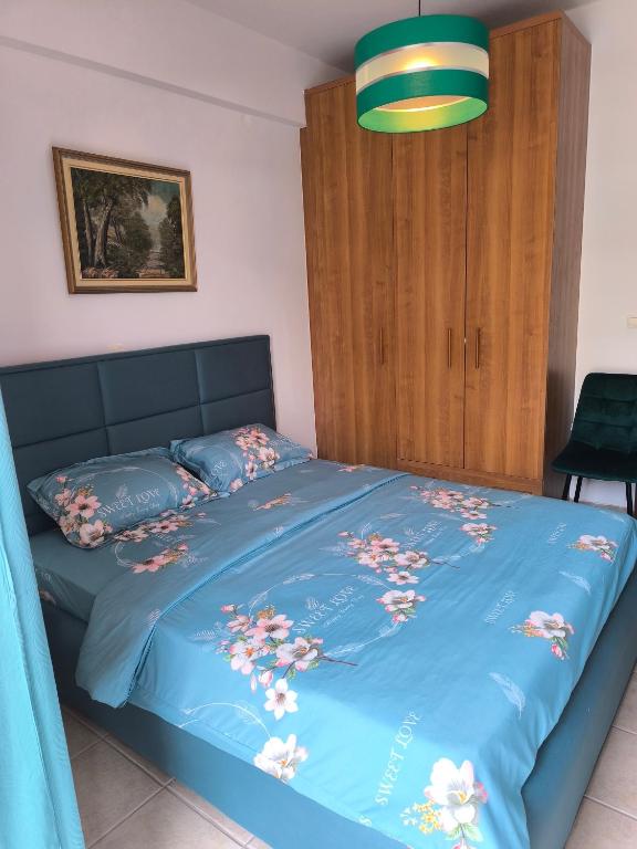 a bed with a blue comforter with flowers on it at Johanna's apartment 2 in Preveza