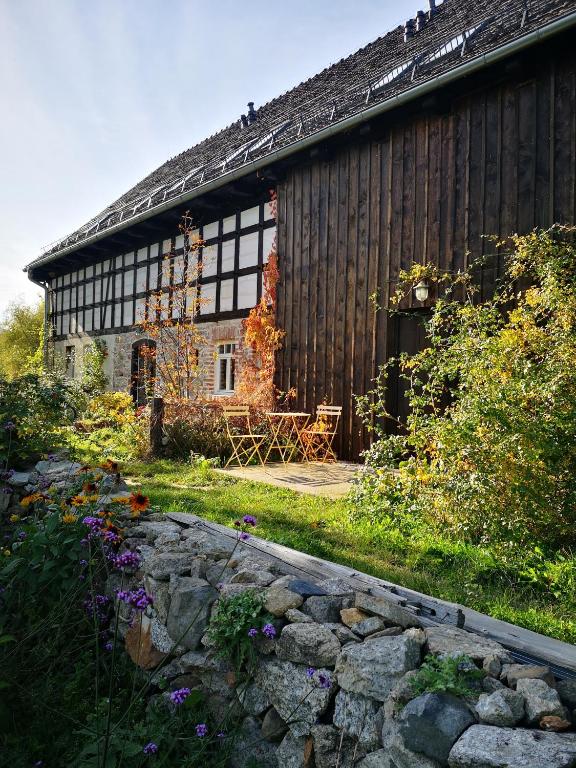 a wooden house with a stone wall in front of it at Noclegi i chleb in Kłopotnica