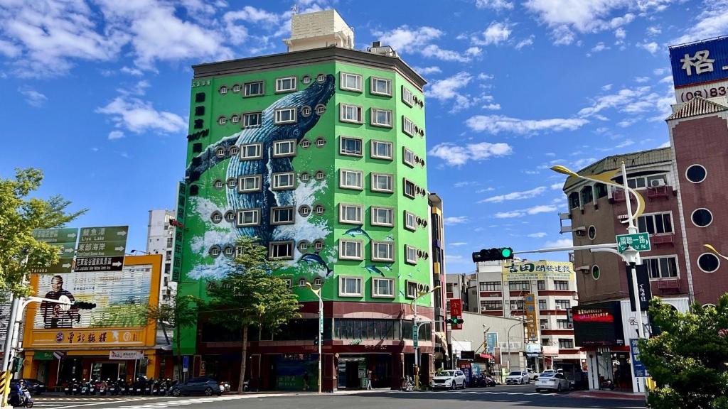 a green building with a painting on the side of it at Hualien Wow Hostel in Hualien City