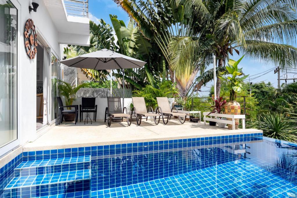 a pool with chairs and an umbrella next to a house at Chaweng Boho Modern in Ban Ko Khwan