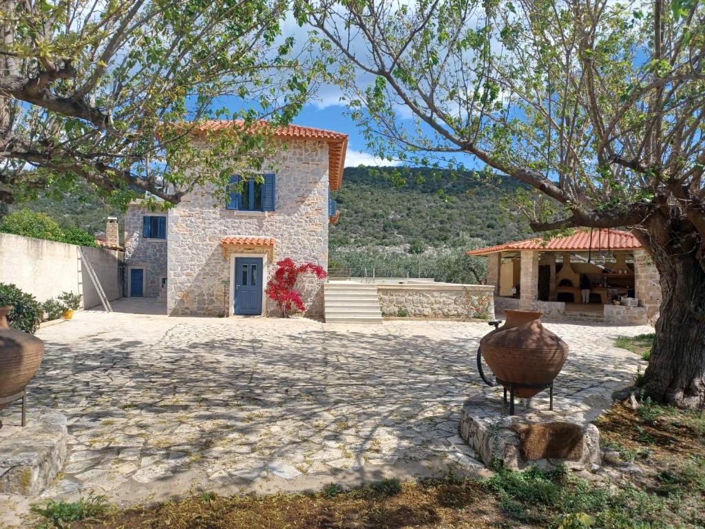 a stone house with a tree in front of it at villa olivedream in Nea Epidavros
