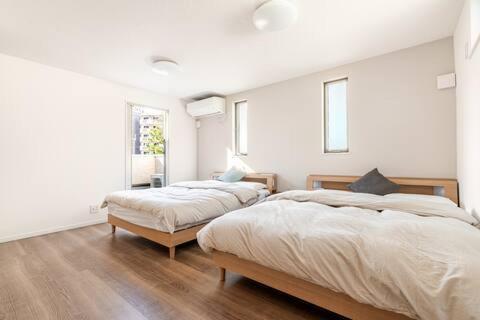 two beds in a room with white walls and wood floors at yuanquanHOTEL in Osaka