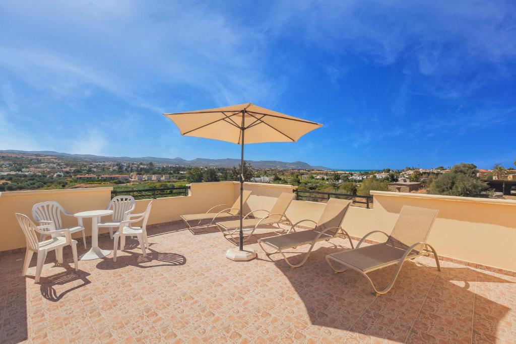 a patio with a table and chairs and an umbrella at Thekla Court in Polis Chrysochous