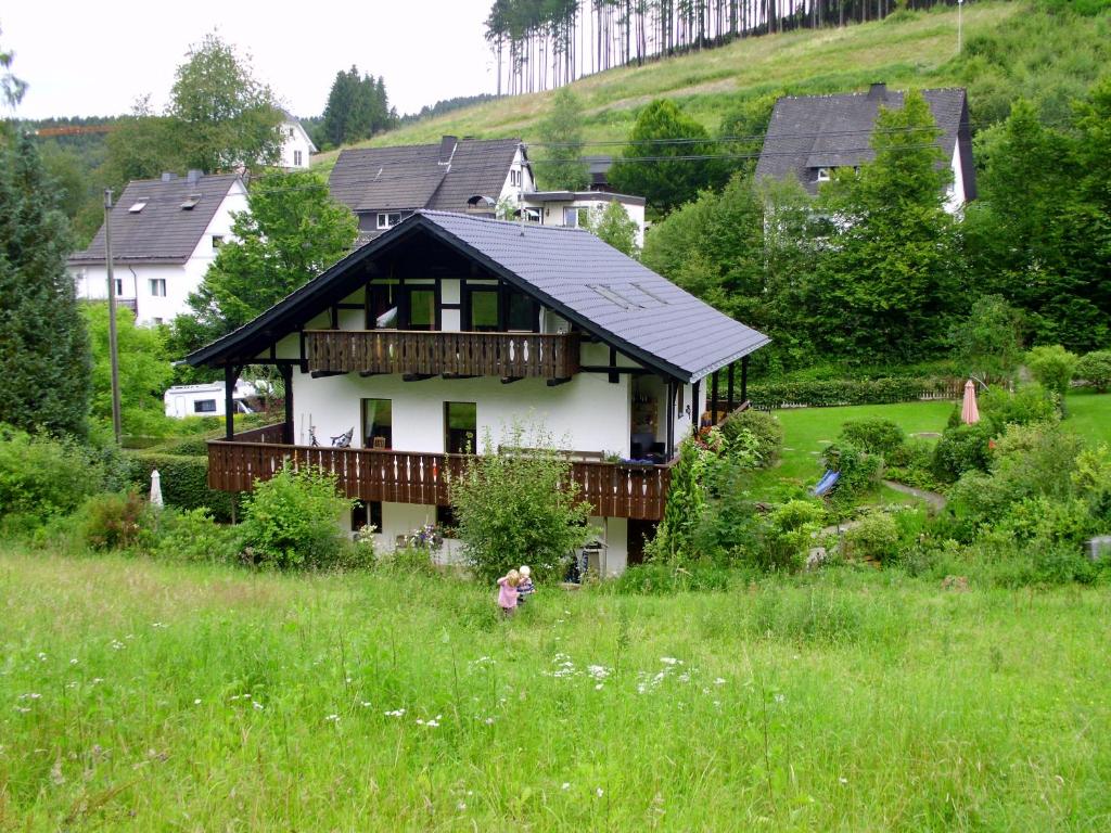 una casa en una colina con una chica parada en un campo en Ferienwohnung Schmallenberg, en Schmallenberg