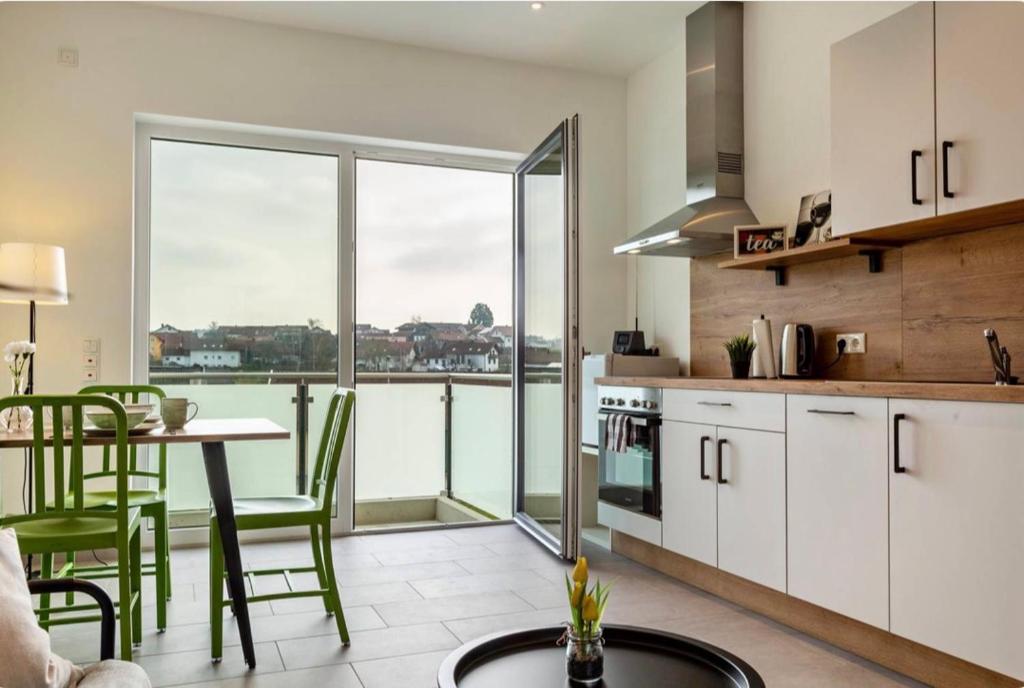 a kitchen with white cabinets and a table with green chairs at Mina in Geratskirchen