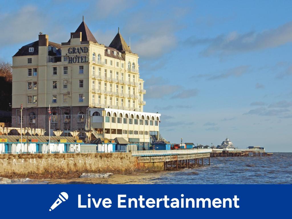 a large building on a pier next to the water at The Grand Hotel in Llandudno
