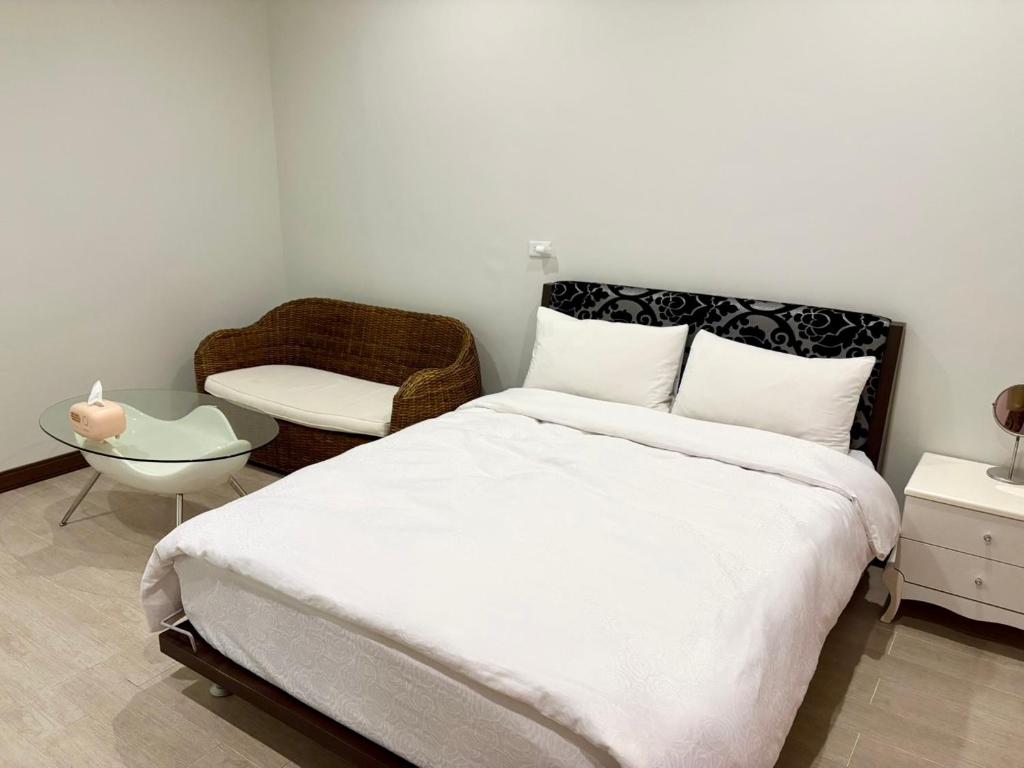 a bedroom with a large white bed and a chair at 日升咖啡民宿 in Gukeng