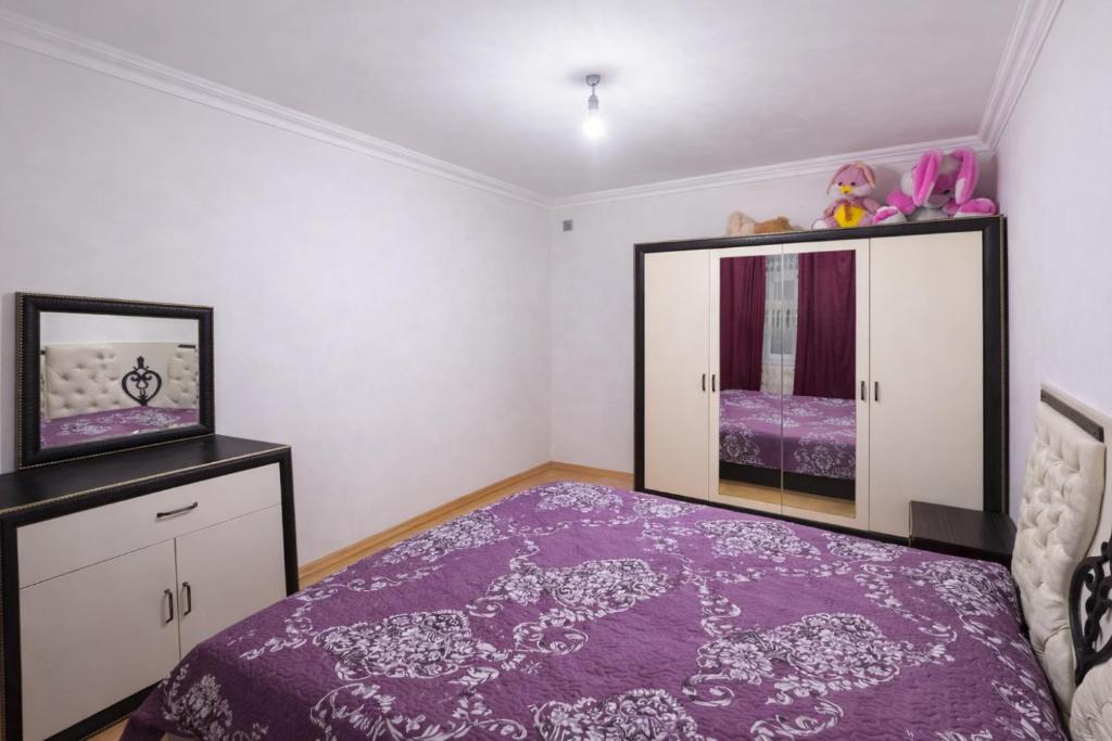 a bedroom with a purple bed and a mirror at İvanovka Eco Home in İvanovka