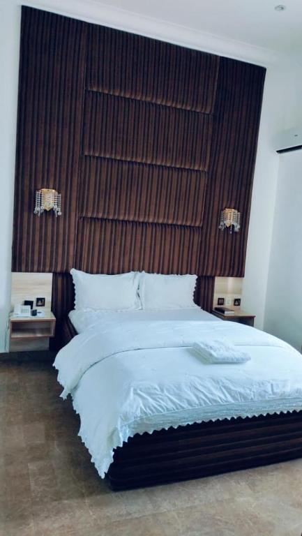 a bedroom with a large bed with a wooden headboard at Meglams Hotel and Suite in Yenagoa