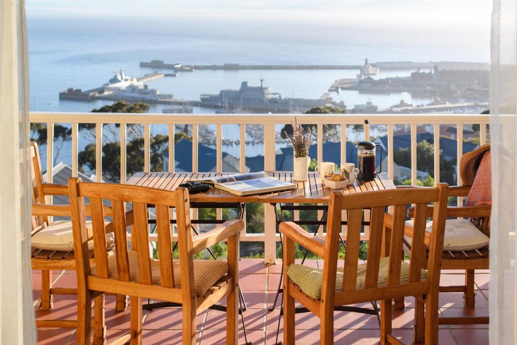 a table and chairs on a balcony with a view of the ocean at Albatross Guest House in Simonʼs Town