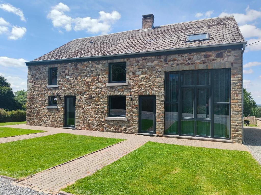 a stone house with glass doors and grass at Chez Amand in Devantave