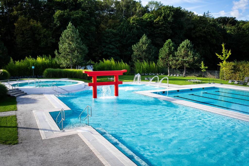 a pool with a red table in the middle of it at Linsberg Asia Hotel, Spa & Therme - Adults Only in Bad Erlach