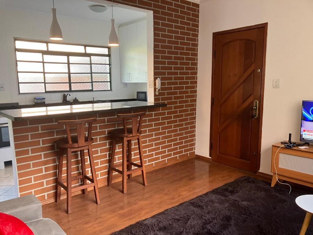 a kitchen with a brick wall and a bar with stools at Panamá 90 - 21 - Região Central in Poços de Caldas