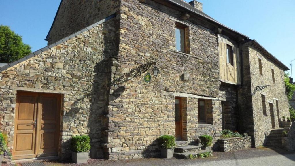 a stone building with a brown door and some plants at Le gué de brocéliande in Plélan-le-Grand