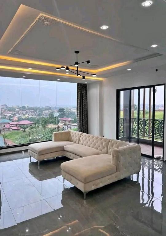 a living room with two couches and large windows at Chambre et apparts meublés, Yaoundé - FOKOU EMANA in Yaoundé