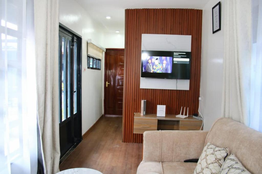 a living room with a couch and a flat screen tv at Maya Stays in Busia
