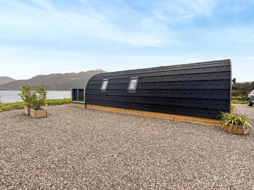a black clad house on the shore of a body of water at Totaig - Uk50717 in Kirkton