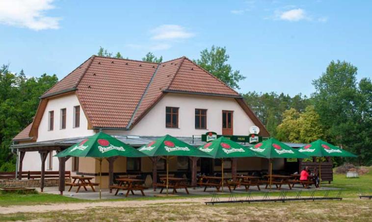 a large building with tables and green umbrellas at Penzion Pecák in Hatín