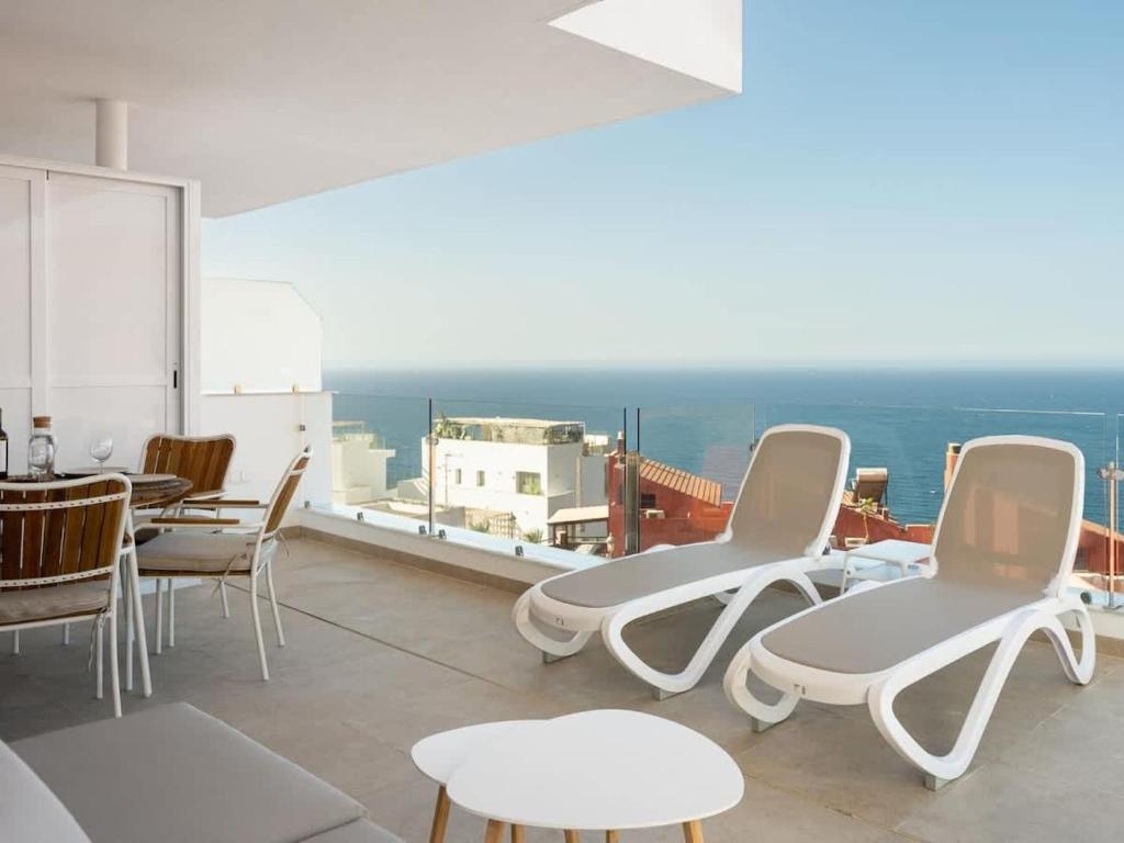 a room with chairs and tables on a balcony at Luxury 2 Bedrooms Apartment Bayview Hills Nerja in Torrox
