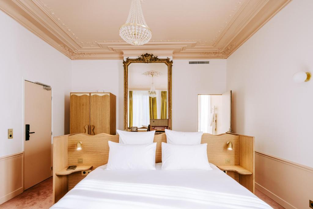 a bedroom with a large white bed and a mirror at Le Charmant Hôtel in Saint-Ouen