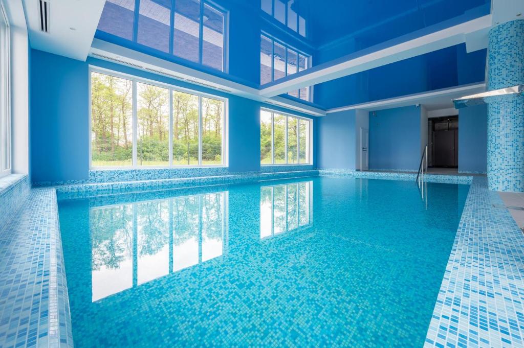 a swimming pool in a building with blue walls and windows at Błękitna Fala Resort in Dąbki