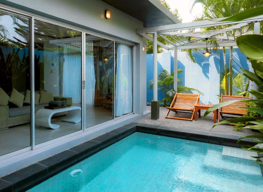 a house with a swimming pool and two chairs at Villa Sonata Phuket in Chalong
